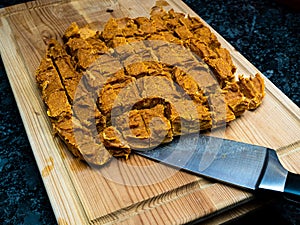 Home made dog treats made of pumpkin on a wooden cutting block with a knife