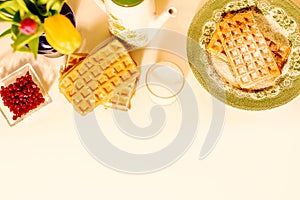 Top view of waffles and pomegranate grains arranged over white background.