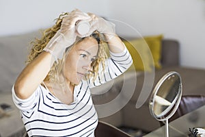 Home made hair dye at home for beauty young caucasian woman looking at the mirror - stay at home concept for coronavirus emergency