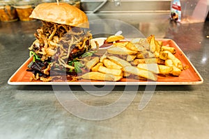 Home made hamburger with lettuce, cheese, beef meat and french fries placed on stainless steel table