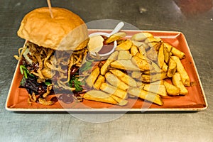 Home made hamburger with lettuce, cheese, beef meat and french fries placed on stainless steel table