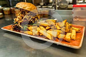 Home made hamburger with lettuce, cheese, beef meat and french fries placed on stainless steel table