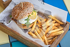 Home made hamburger with lettuce fried egg and fries in wooden bowl