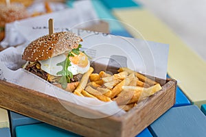Home made hamburger with lettuce fried egg and fries in wooden bowl. Gourmet street food concept