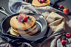 Home made pancakes with berries on metal frying pan decorated wi