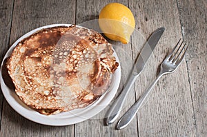 Home made pancakes with lemon and sugar topping seen against a textured wooden background