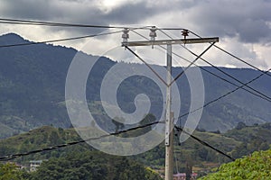 Home-made power pole with wires and old insulators against the backdrop of mountains and sky