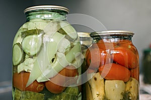 Home made preserves on neutral background. Canned tomatoes, cucumbers, cauliflower, bell peppers