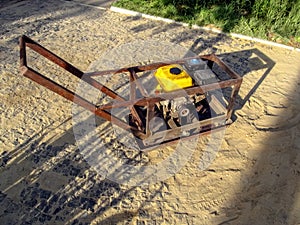Home-made vibratory rammer stands on a site with newly laid granite paving stones. Do-it-yourself concept. Creation of gasoline