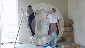 Home makeover and renovation: young happy couple painting their new house interiors using paint rollers