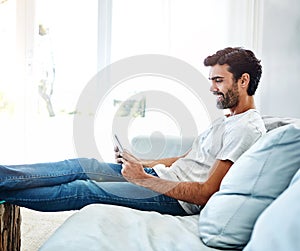 Home, man and tablet on sofa for networking, chat and online conversation with contact. Living room, male chatter and photo