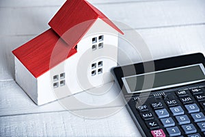Home model and calculator on white background. Buying house concept. Closeup