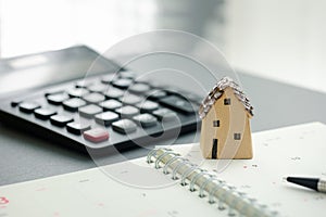 home model on notebook with pen and calculator