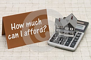 Home Mortgage Affordability, A gray house, brown card and calculator on stone background