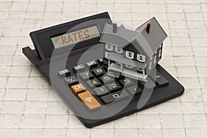 Home Mortgage Interest Rates, A gray house and calculator on stone background