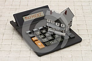Home Mortgage Payment, A gray house and calculator on stone back
