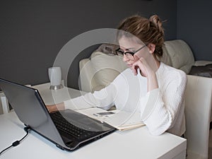 Home office, business girl with glasses working on a laptop.