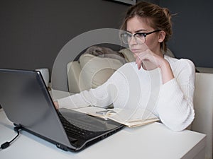 Home office, business girl with glasses working on a laptop.