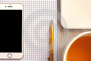 Home office concept. Laptop, notebook, smartphone, notepad, tea cup, pen on wooden background