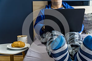 Home office concept - man working from his bed with breakfast