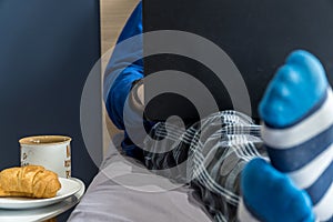 Home office concept - man working from his bed with breakfast