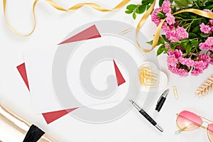 Home office desk with blank white card, red craft paper envelope, golden stationery and feminine accessories on white background.