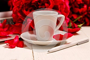 Home office desk with laptop, pink peonies, mug of coffee, stationery, glasses on a white background