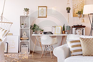 Home office desk with oldschool telephone, typewriter and fresh plants placed in white living room interior