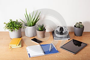 Home office desk with tablet computer smartphone notebook houseplants, working space at home