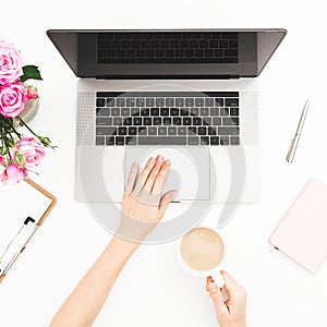 Home office desk. Woman workspace with female hands, laptop, pink roses bouquet, and diary on white background. Flat lay. Top view