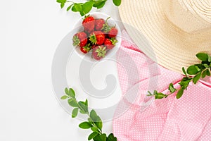 Home office desk workspace with straw hat, pink cloth, strawberries, branch of barberry on white background. Flat lay, top view