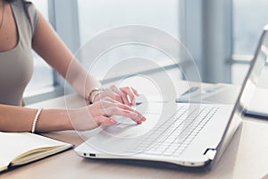 Home-office of a distance employed female freelancer, typing text, using her electronic device.