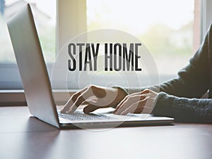 Home office with freelancer hands with laptop and text Stay home