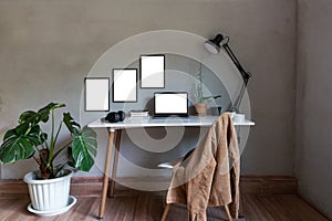 Home office with mock up laptop and chair, book on desk decor white frame as lamp light and monstera tree pot, plants house with