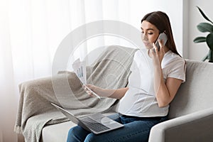 Home Office. Pregnant Lady Working With Papers And Laptop In Living Room