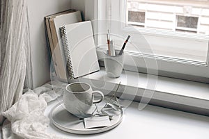 Home office still life. Blank diary and business card mockup. Cup of coffee, olive tree branch on tray. Books and