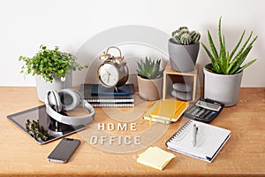 Home office text desk with tablet computer smartphone notebook houseplants, working space at home