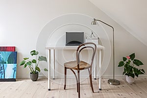 Home office. Vintage chair at white desk with laptop computer.