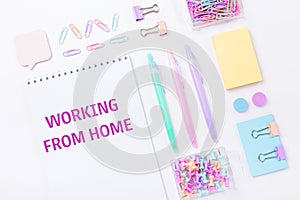 Home office workplace with notebook and pastel colorful study accessories on pink background. Working from home concept