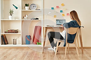 Home office. Young woman in casual clothes sitting at office desk, working or studying working or studying on laptop at