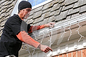 Home owner hanging exterior Christmas lights