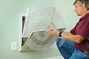 Home owner putting new air filter on air conditioner