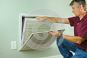 Home owner replacing air filter on air conditioner