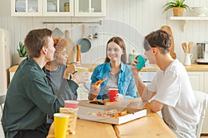 Home party. Friends spending time together having fun laughing communicating at home. Happy diverse group eating pizza