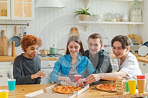 Home party. Overjoyed diverse friends eating ordered pizza for home party. Happy group mixed race young buddies enjoying