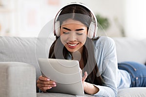 Home Pastime. Asian Girl Using Digital Tablet And Listening Music In Headphones