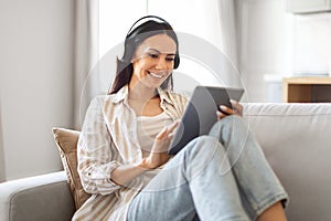 Home Pastime. Happy Woman Wearing Headphones Relaxing With Digital Tablet On Couch