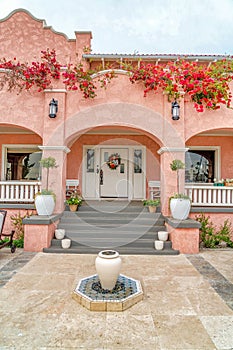 Home with pink exterior walls arches at the porch and front door with sidelights