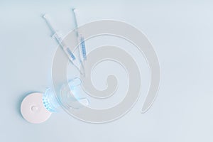 Home portable equipment with blue light and syringes with teeth whitening product on blue background
