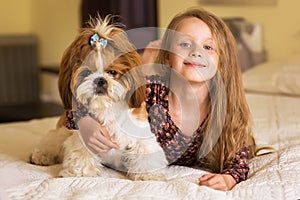Home portrait of cute child hugging with puppy of dog on the sofa